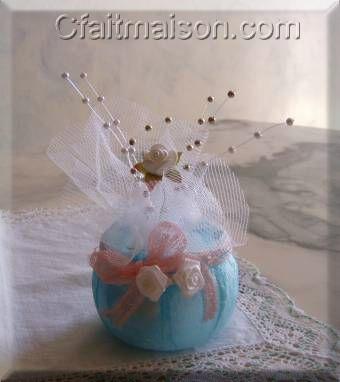 Prsentation de drages dans un pot de laitage en plastique recouvert d'une paisseur de serviette bleue colle, finition avec un noeud rose et de fleurs blanches.
