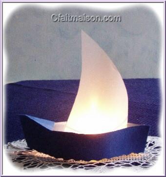 Photophore en forme de bateau avec voile en papier calque et bougie allumée.