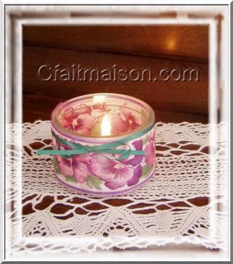 Photophore dans un pot de yaourt en verre bas entouré d'un ruban large fleuri, finition avec un fin noeud de ruban vert.