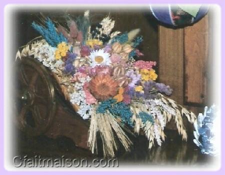 Composition de fleurs sches dans un chariot en bois.