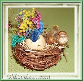 Coquille d'œuf avec des petites fleurs sèches et oiseaux dans un nid fait maison avec des tiges de vigne vierge.