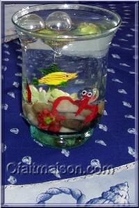 Vase rempli d'eau avec galets, plantes et sujets en verre