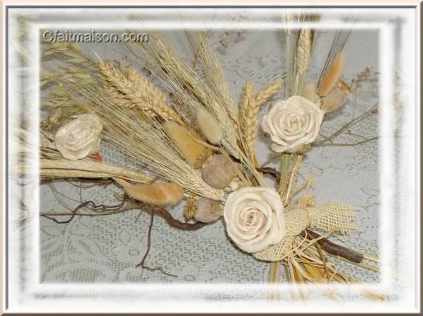 Composition sans vase de gramines et fausses roses en fibres naturelles.