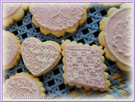 Biscuits avec glaage royal rose et dessins raliss sur ce glaage en glaage blanc.