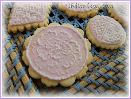 Biscuits avec glaage royal rose et dessins raliss sur ce glaage en glaage blanc.